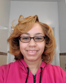 headshot of a woman with glasses and a pink sweatshirt smiling into the camera