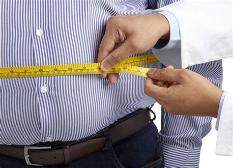 man wearing a striped shirt has waist circumference measured by a doctor with a flexible tape measure
