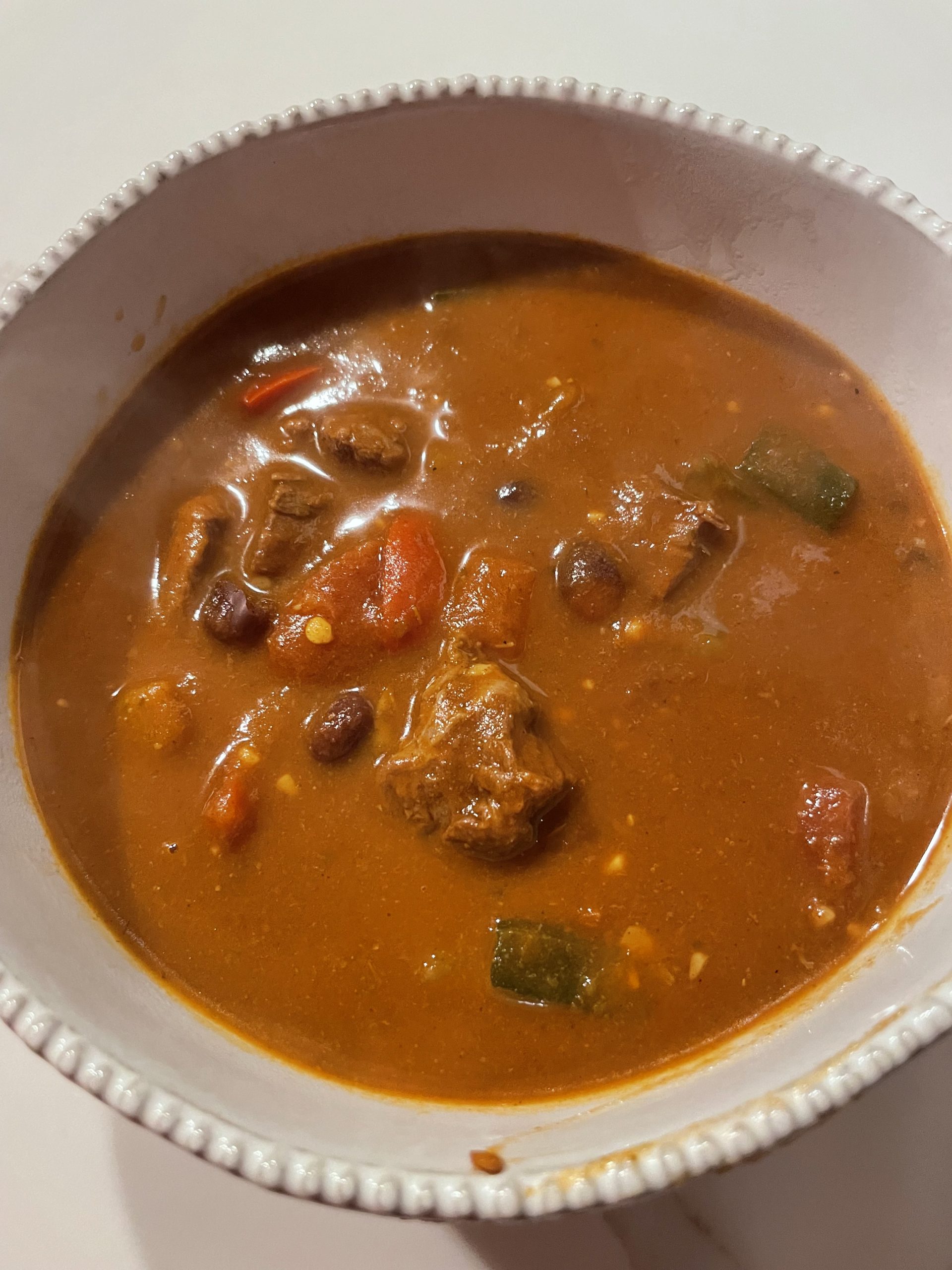 White porcelain bowl filled with chili on a white counter top